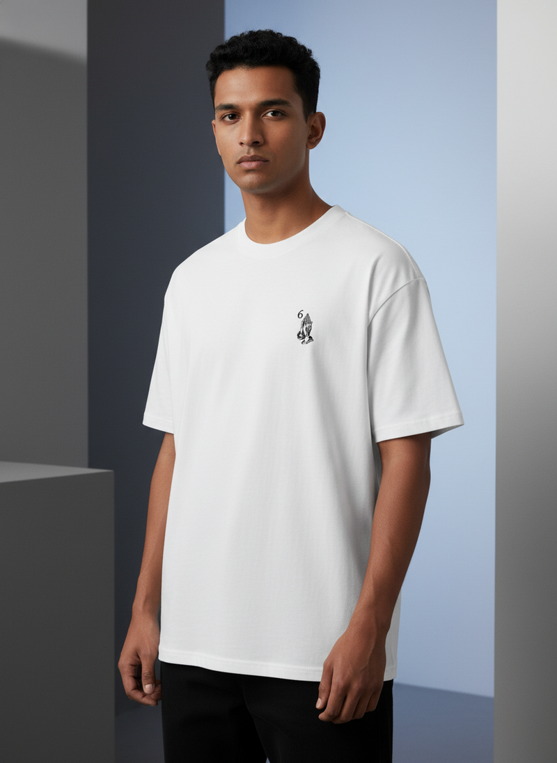 Diverse model wearing an oversized white Blessed tee in an elegant, minimalist setting with black, white, and gray tones.