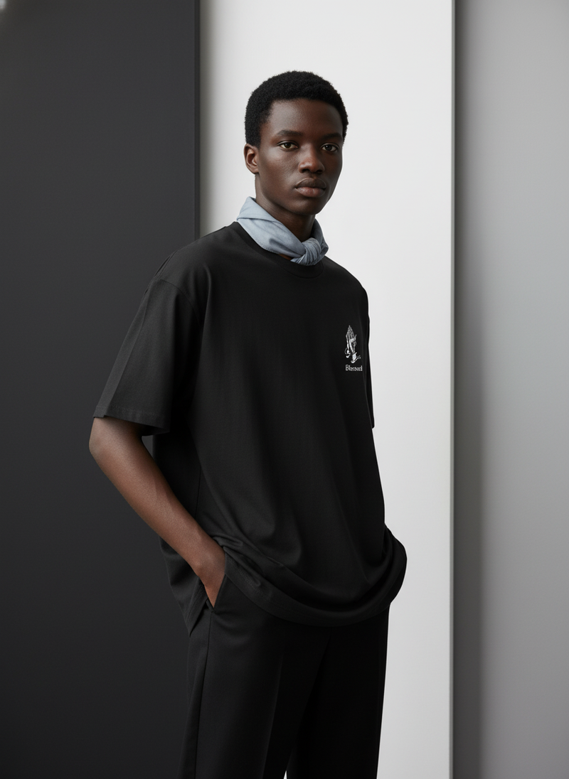 Diverse model wearing an oversized white tee with "Blessed" printed on it, against a minimalist black, white, and gray backgr